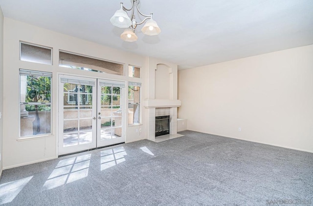 unfurnished living room featuring carpet floors, a fireplace, a notable chandelier, and plenty of natural light