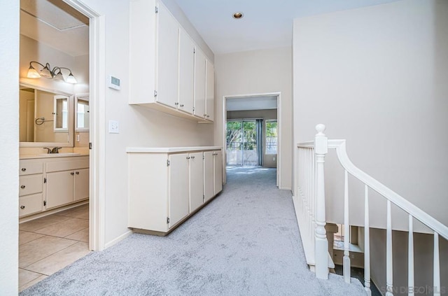 corridor featuring sink and light carpet