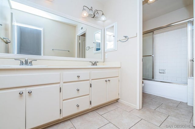 bathroom featuring tile patterned flooring, vanity, and bath / shower combo with glass door