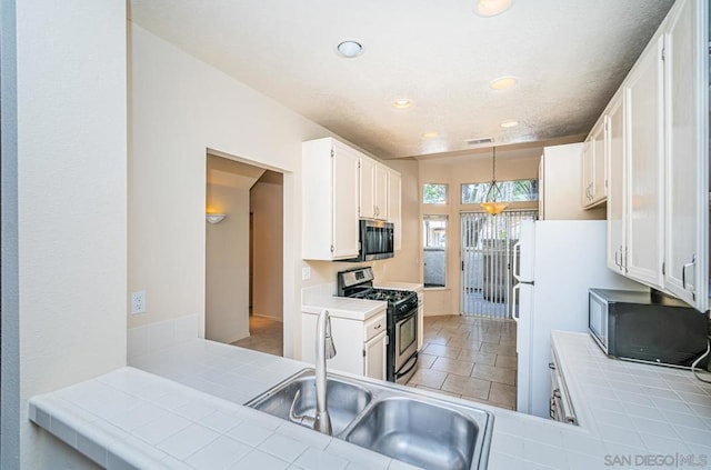 kitchen featuring white cabinetry, kitchen peninsula, stainless steel appliances, tile countertops, and sink