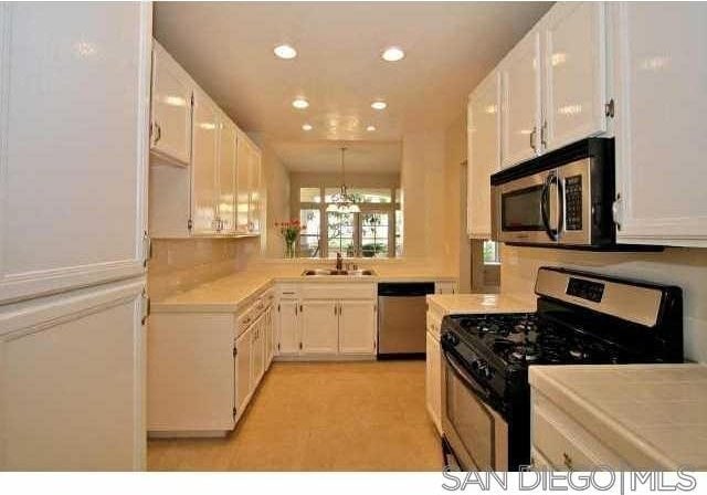 kitchen featuring appliances with stainless steel finishes, sink, a chandelier, and white cabinets