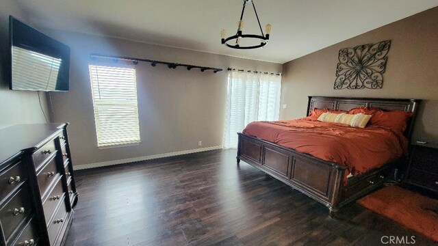 bedroom featuring an inviting chandelier, vaulted ceiling, and dark hardwood / wood-style floors