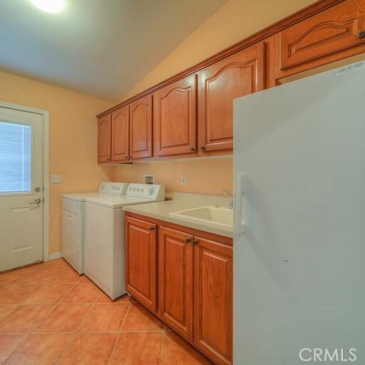 washroom featuring cabinets, light tile patterned flooring, washer and clothes dryer, and sink