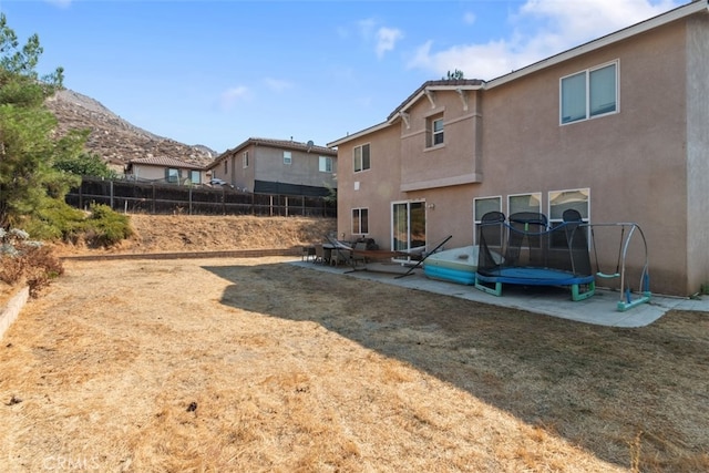 rear view of house with a lawn, fence, a patio, and stucco siding