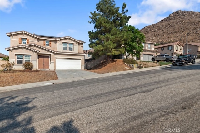 view of front of house with roof mounted solar panels, driveway, an attached garage, and a mountain view