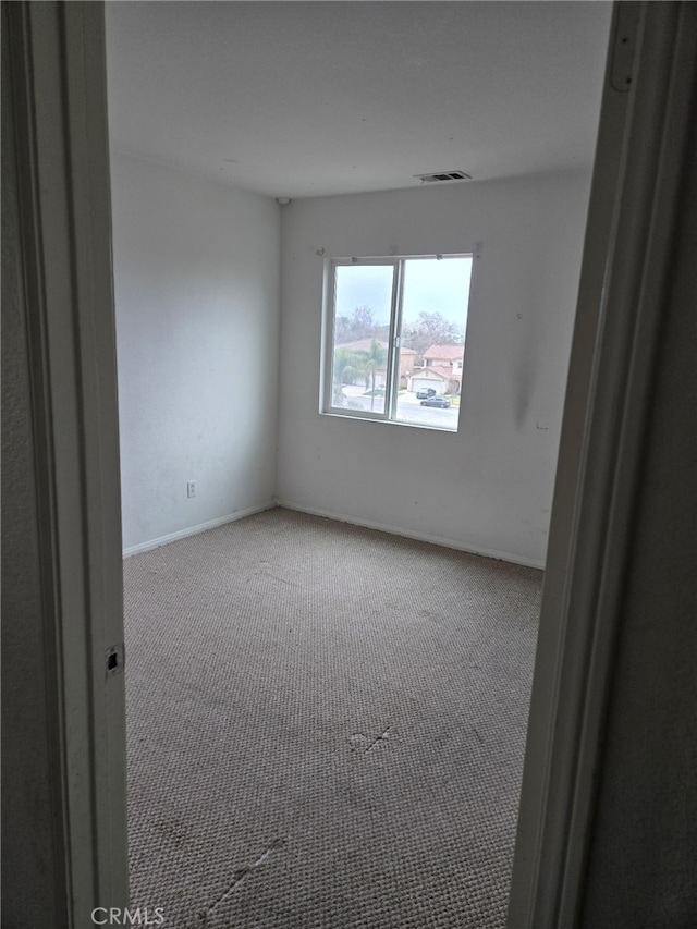 carpeted empty room featuring visible vents