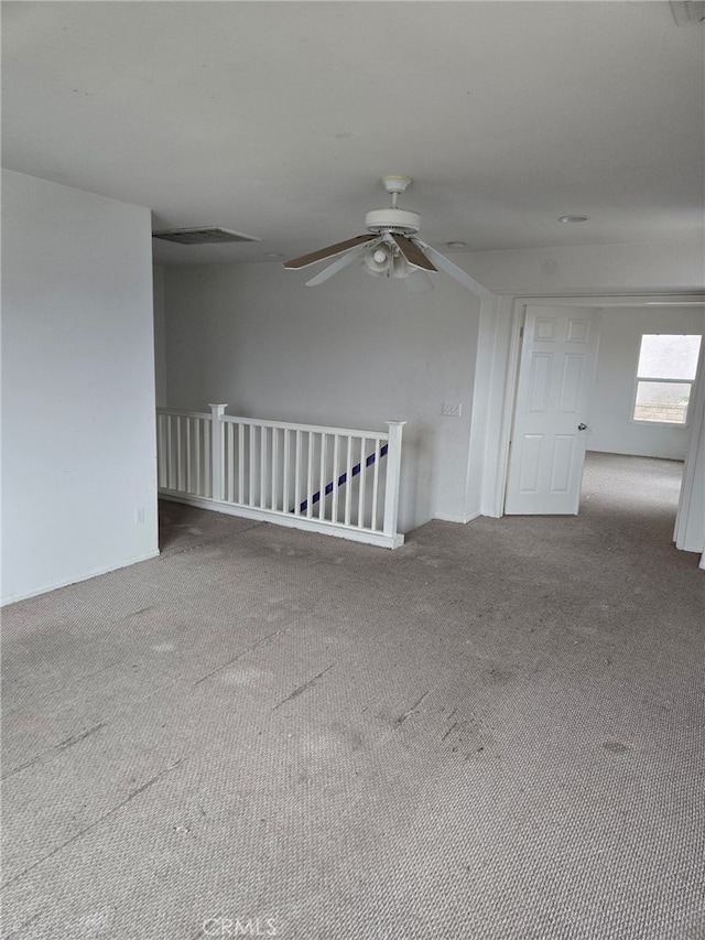 empty room featuring carpet floors, visible vents, and a ceiling fan