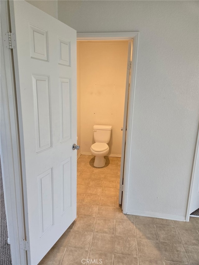 bathroom featuring toilet, baseboards, and tile patterned floors