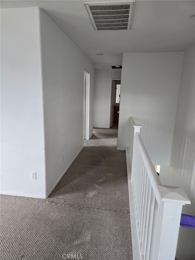 hallway featuring carpet flooring, an upstairs landing, visible vents, and baseboards