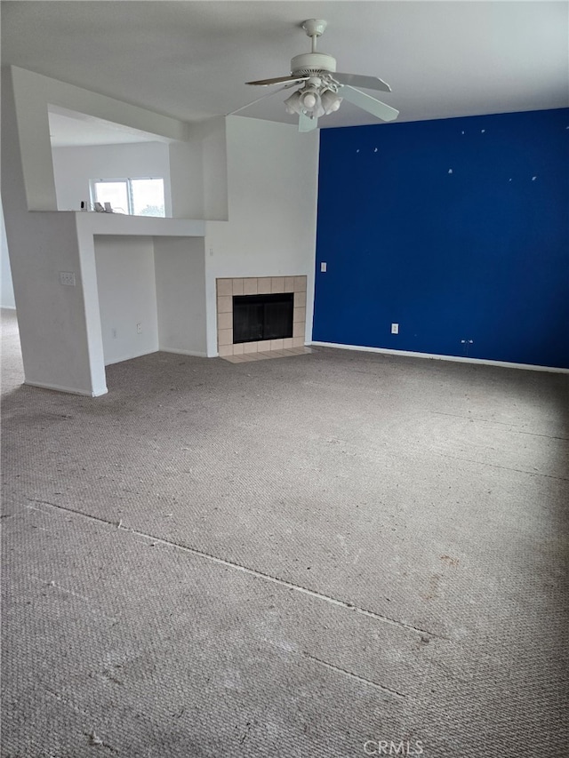 unfurnished living room featuring carpet floors, ceiling fan, and a tiled fireplace