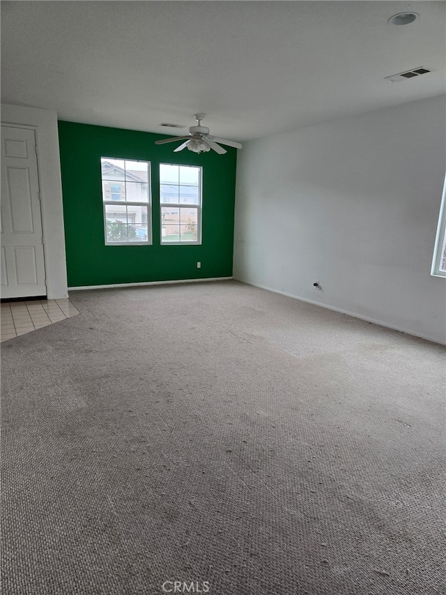 spare room with carpet floors, visible vents, and ceiling fan