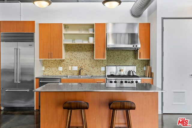 kitchen with a kitchen island, extractor fan, appliances with stainless steel finishes, and a kitchen bar