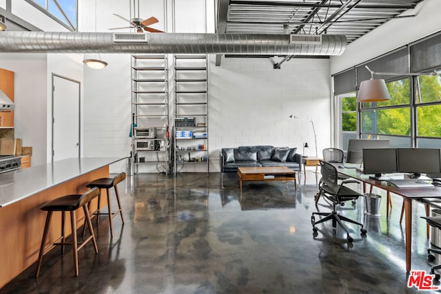 interior space featuring ceiling fan, a towering ceiling, and a healthy amount of sunlight