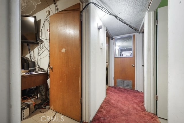 corridor with a textured ceiling and carpet flooring