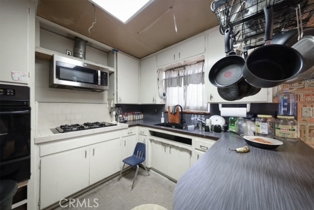 kitchen with black oven, sink, white gas cooktop, and white cabinets