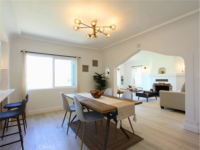 dining space with light hardwood / wood-style flooring, a notable chandelier, and crown molding