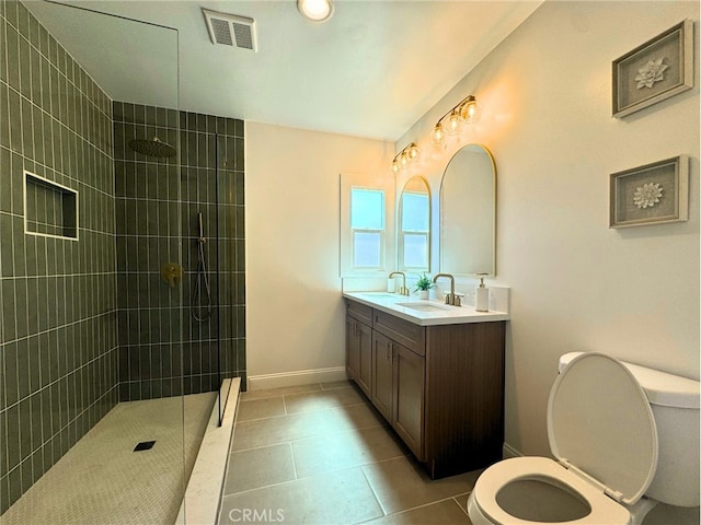 bathroom with tiled shower, vanity, toilet, and tile patterned floors