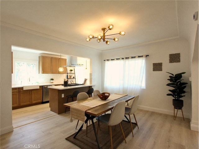 dining room featuring a notable chandelier, light wood-type flooring, ornamental molding, and sink