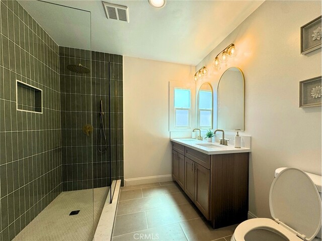 bathroom with a tile shower, tile patterned floors, vanity, and toilet