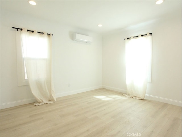 spare room with light hardwood / wood-style floors and an AC wall unit