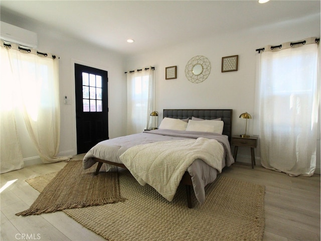 bedroom featuring a wall mounted AC and light hardwood / wood-style flooring