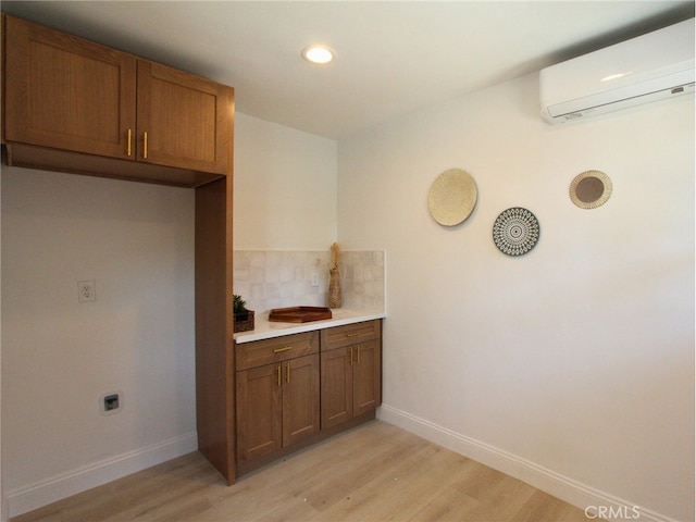 kitchen with light hardwood / wood-style flooring, backsplash, and an AC wall unit