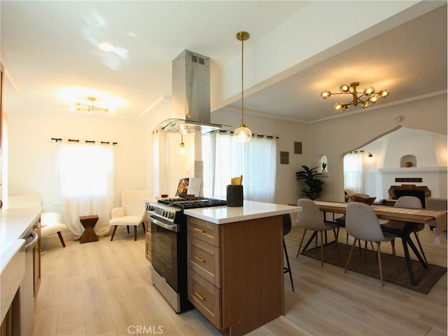 kitchen featuring hanging light fixtures, light hardwood / wood-style flooring, appliances with stainless steel finishes, extractor fan, and a large fireplace