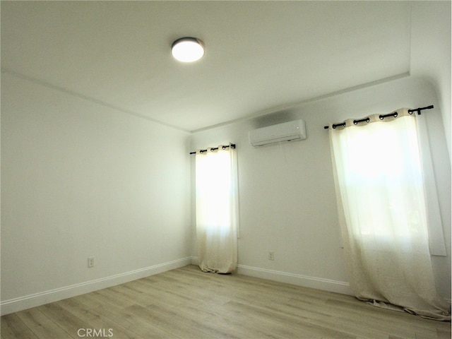 spare room featuring light hardwood / wood-style flooring and a wall mounted air conditioner