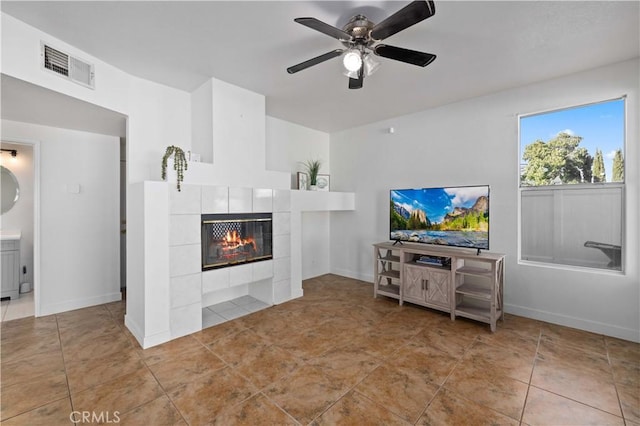 living room featuring ceiling fan and a tile fireplace