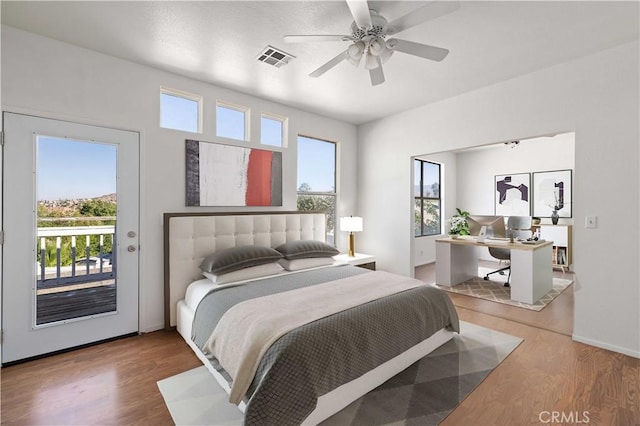 bedroom with wood-type flooring, access to outside, and multiple windows