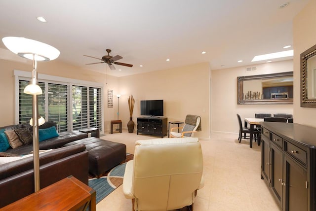 living room with ceiling fan and a skylight