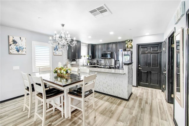 dining room with an inviting chandelier, light hardwood / wood-style floors, and sink