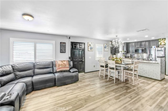 living room with a notable chandelier and light wood-type flooring