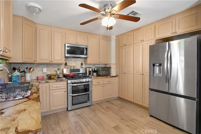 kitchen with sink, light hardwood / wood-style flooring, backsplash, appliances with stainless steel finishes, and ceiling fan