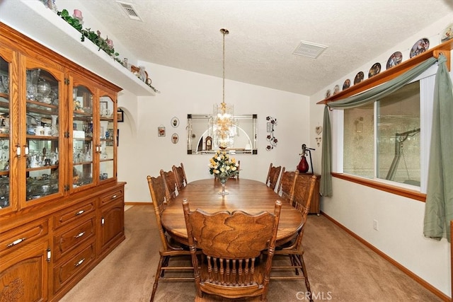 carpeted dining space with a textured ceiling, vaulted ceiling, and an inviting chandelier