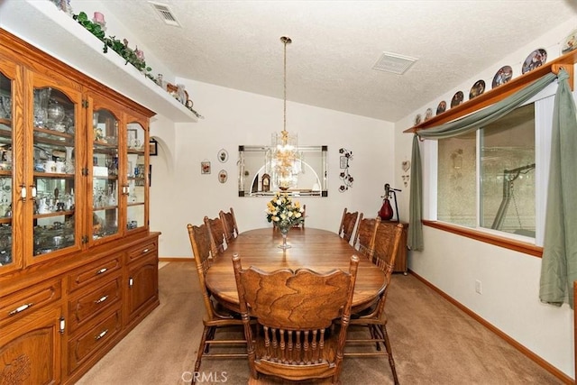 dining area with baseboards, a chandelier, a textured ceiling, light colored carpet, and lofted ceiling