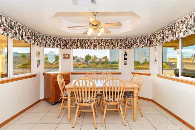 dining space with baseboards, light tile patterned floors, visible vents, a raised ceiling, and ceiling fan