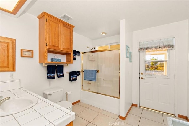 full bathroom featuring shower / bath combination with glass door, visible vents, toilet, a sink, and tile patterned floors