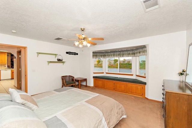 bedroom with visible vents, ceiling fan, light carpet, and a textured ceiling