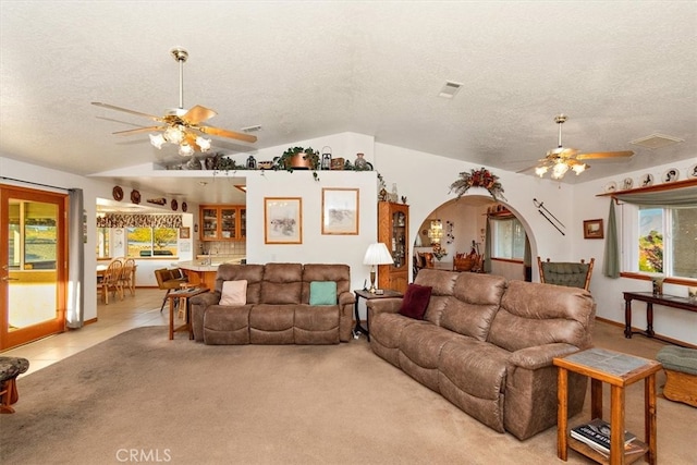 living room featuring lofted ceiling, ceiling fan, light tile patterned flooring, and a textured ceiling