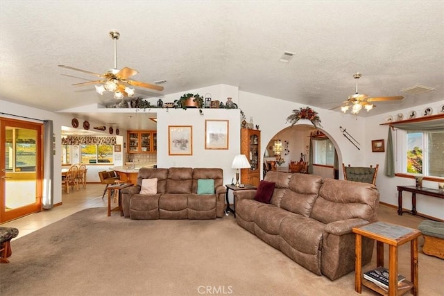 carpeted living room with visible vents, a textured ceiling, a ceiling fan, and lofted ceiling