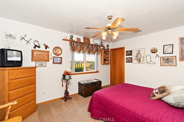 bedroom with ceiling fan, carpet floors, and a textured ceiling