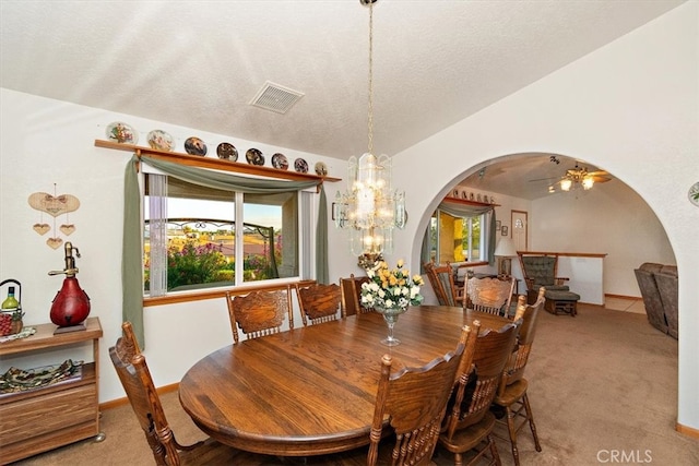 carpeted dining area featuring a textured ceiling and ceiling fan with notable chandelier