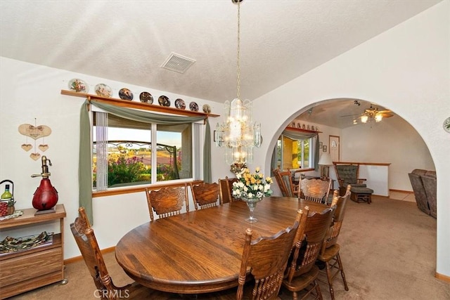 dining room featuring arched walkways, visible vents, light carpet, lofted ceiling, and baseboards