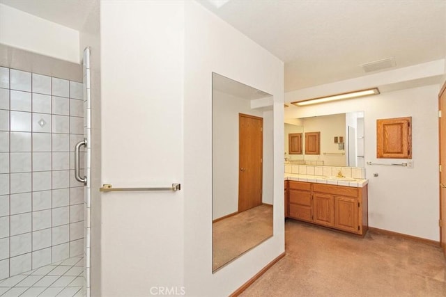 bathroom with a shower stall, vanity, baseboards, and visible vents