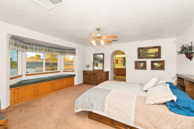 bedroom with connected bathroom, ceiling fan, light colored carpet, and a textured ceiling