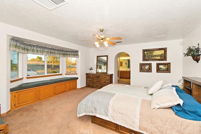 bedroom with arched walkways, light colored carpet, and a textured ceiling