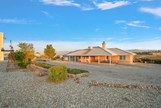 farmhouse inspired home featuring a mountain view, stucco siding, a chimney, and a tile roof