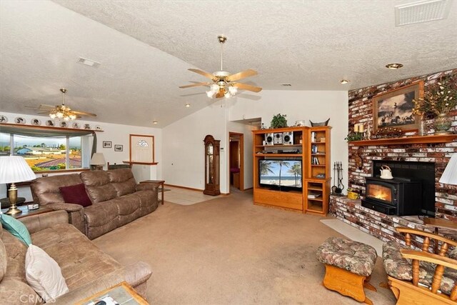living area with visible vents, a wood stove, a ceiling fan, a textured ceiling, and vaulted ceiling
