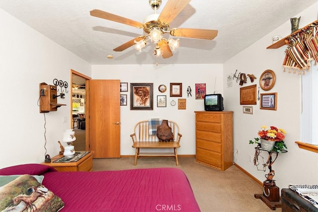 bedroom with ceiling fan, light colored carpet, and a textured ceiling